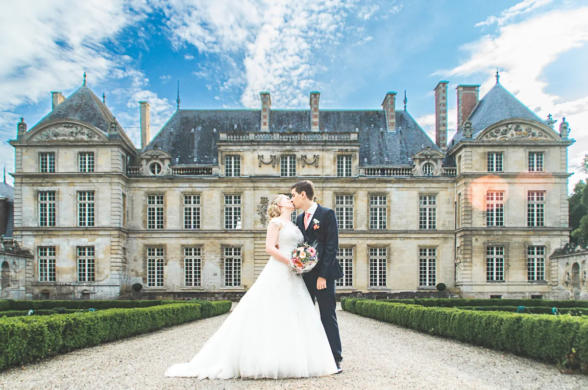 Les mariés s'échangent un baiser devant le Chateau de Raray, Le photographe à fait le déplacement depuis Toul