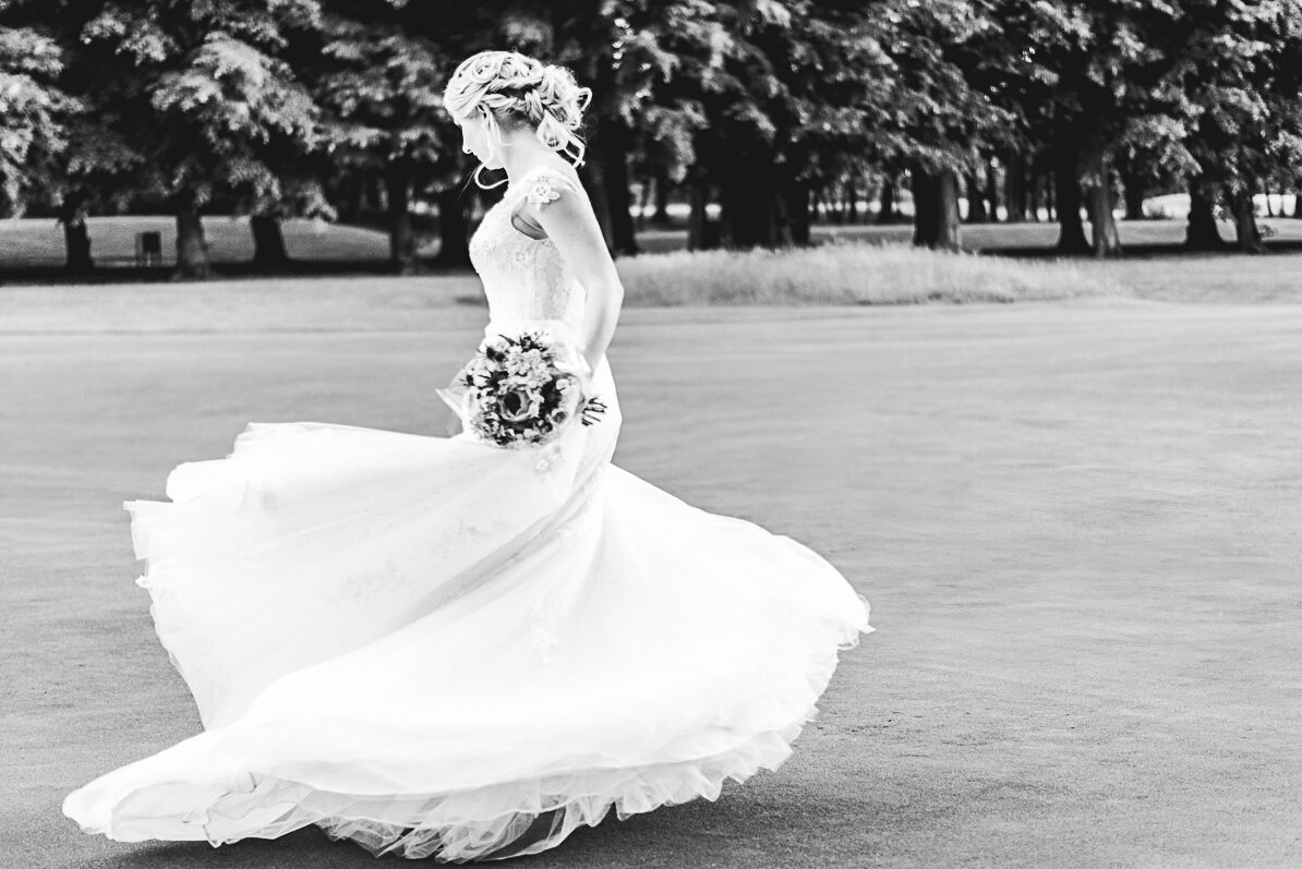 La robe au vent - Photographie de mariée à Nancy La mariée tournoie dans sa robe, son bouquet à la main sur le golf du chateau de Raray
