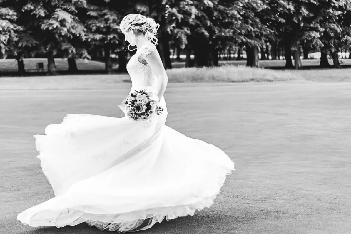 La mariée tournoie dans sa robe, son bouquet à la main sur le golf du chateau de Raray