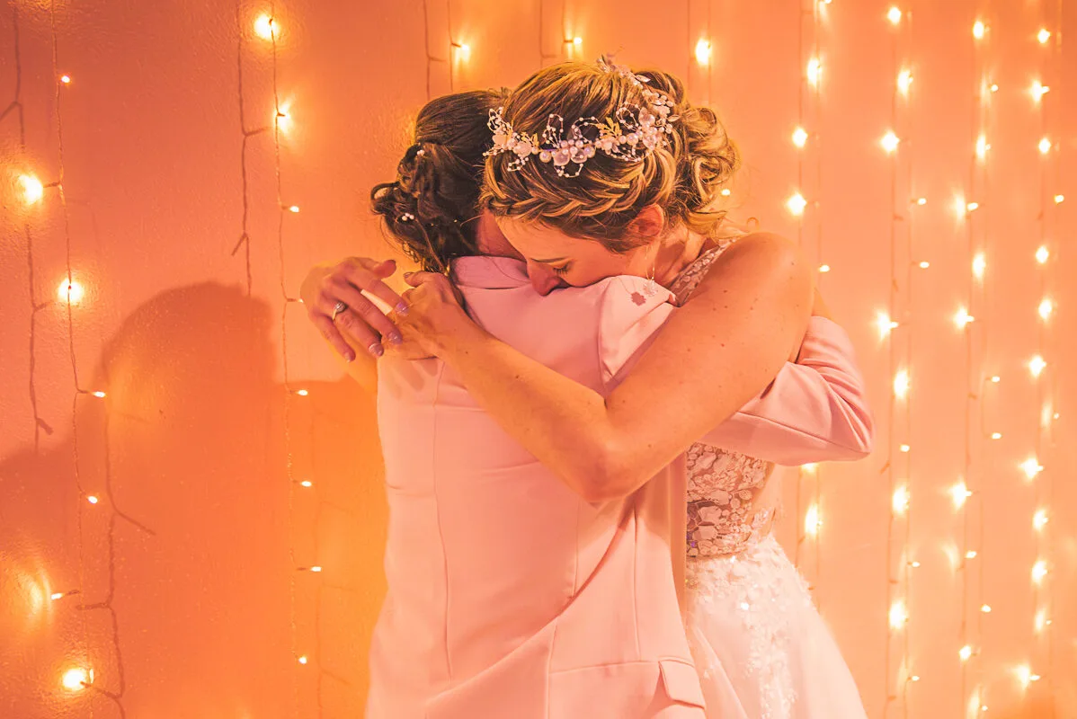 La marié fait un calin empli de tendresse à sa meilleure amie - cette photo est d'une douceur infinie avec ses couleurs orangée et rose.