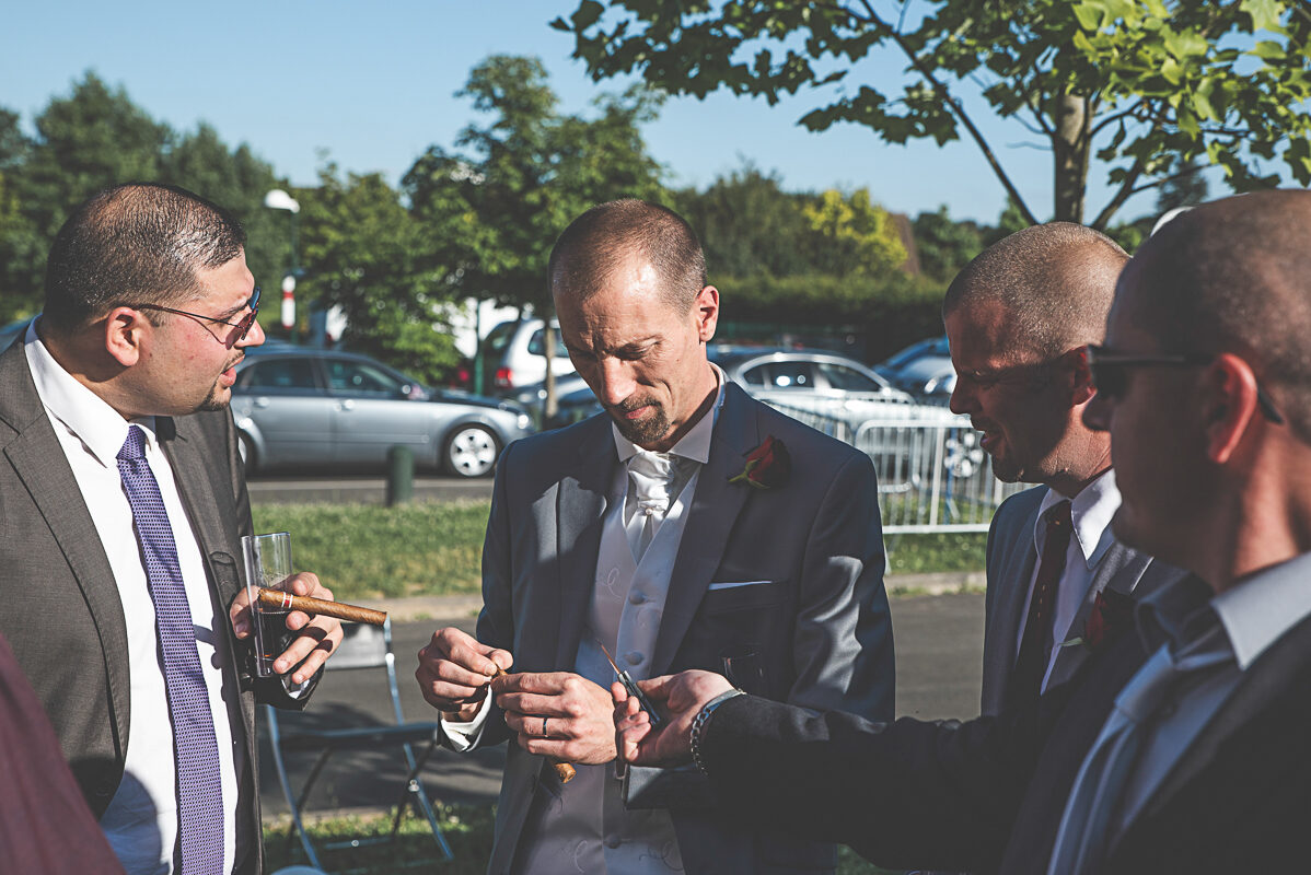Un cigare entre gentlemen -Photographie de mariage à Nancy Le marié et ses témoins préparent un cigare et discutent