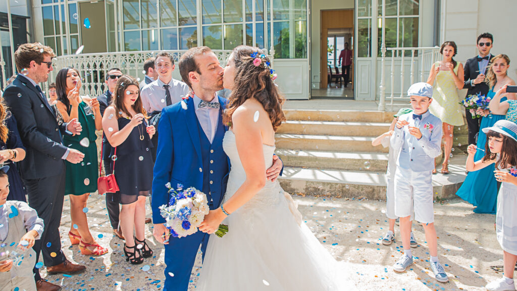 Des bulles et des fleurs entoures nos jeunes mariés qui s'embrassent à la sortie de la maire -Photographe de mariés romantiques à Nancy